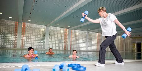 Patienten trainieren Wassergymnastik im Schwimmbad