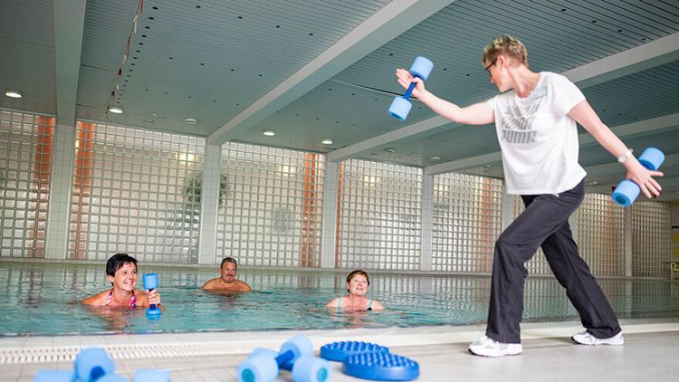 Patienten trainieren Wassergymnastik im Schwimmbad