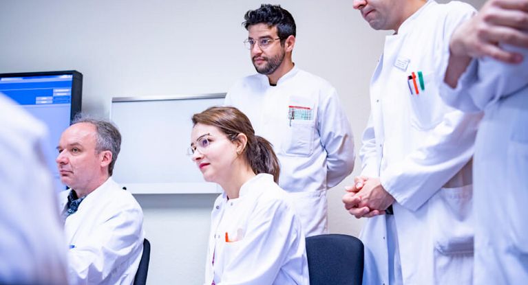 Ärztinnen und Ärzte hören während einer Besprechung konzentriert zu