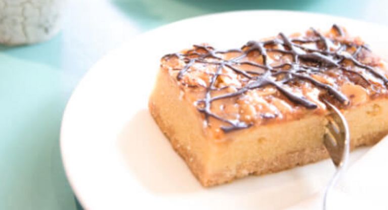 ein Stück Kuchen und eine hohe Tasse Kaffee mit Sahne