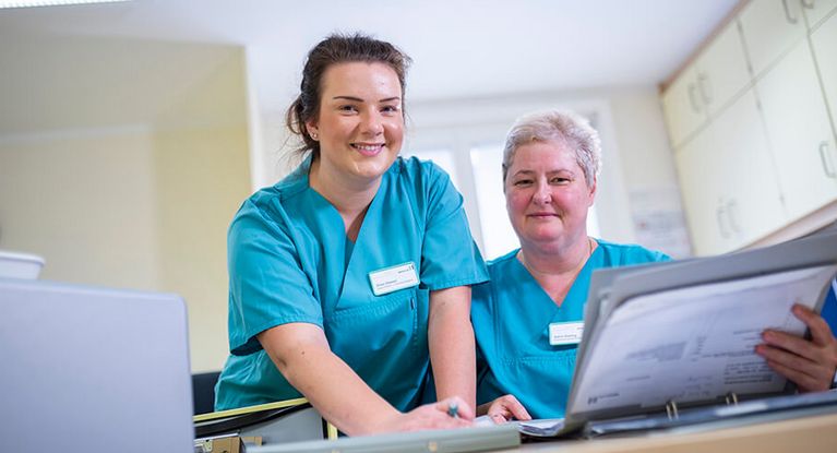 Zwei weibliche Pflegekräfte bereiten die Schichtübergabe vor