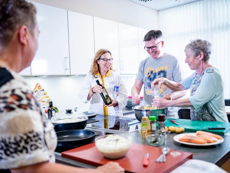 Patienten und Ernährungsberaterin kochen gemeinsamin der Lehrküche