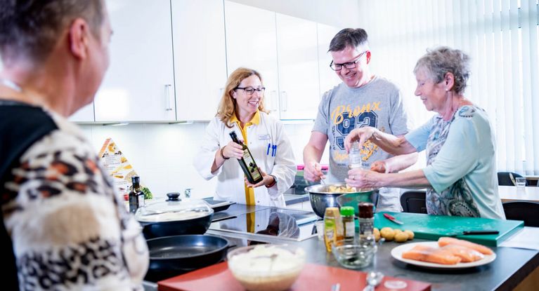 Patienten und Ernährungsberaterin kochen gemeinsamin der Lehrküche