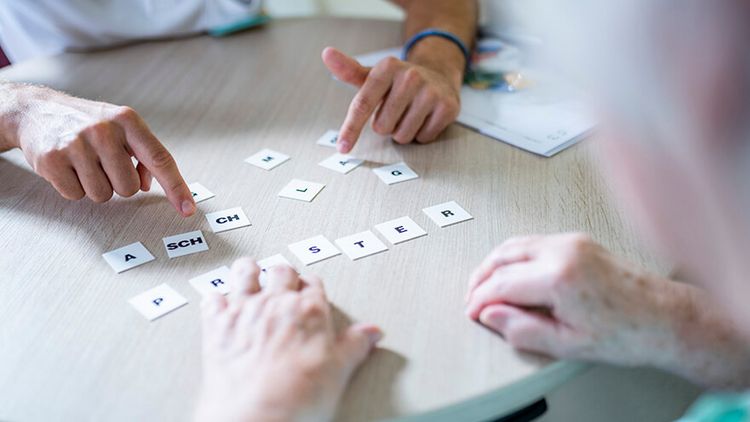 Logopädin legt Worte aus Buchstaben beim Aphasietraining