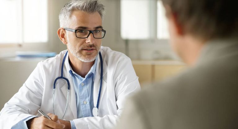 Bärtiger mittelater Arzt spricht mit einem Patienten