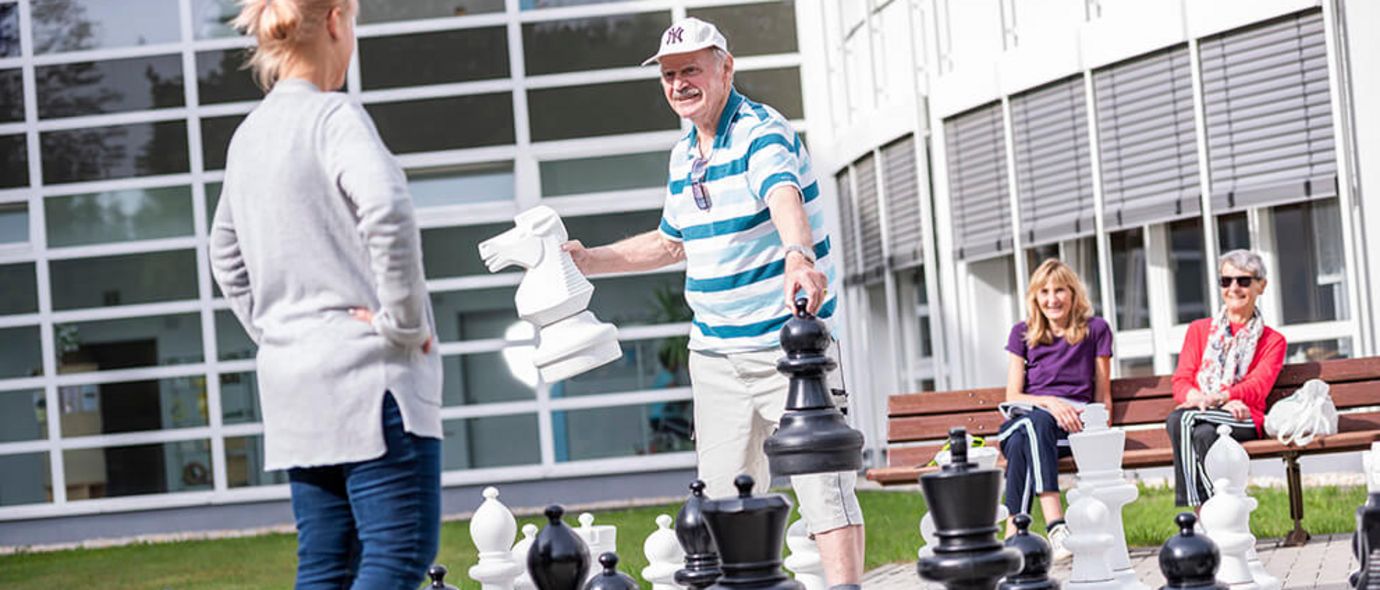 Patienten spielen Schach im Garten der Klinik