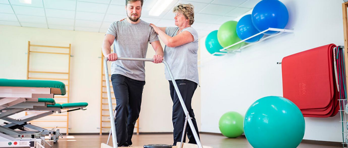 Therapeutin unterstütz Patientin beim Gehtraining