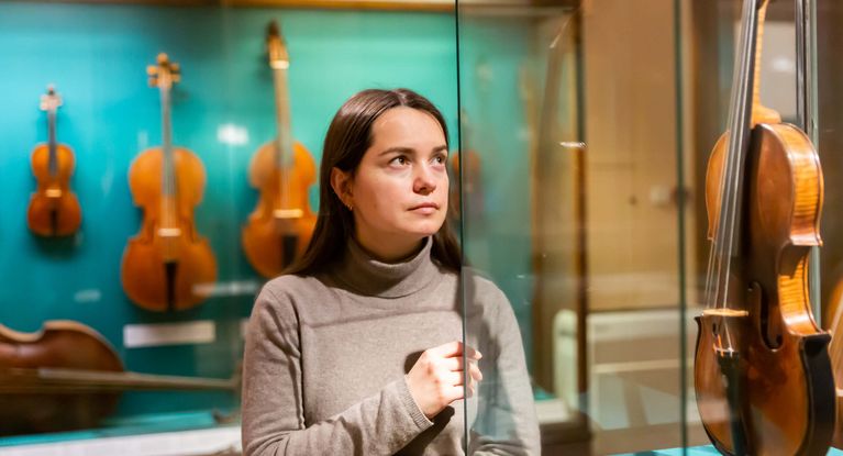 Junge weibliche Besucherin betrachten Geigen im Musikalienmuseum